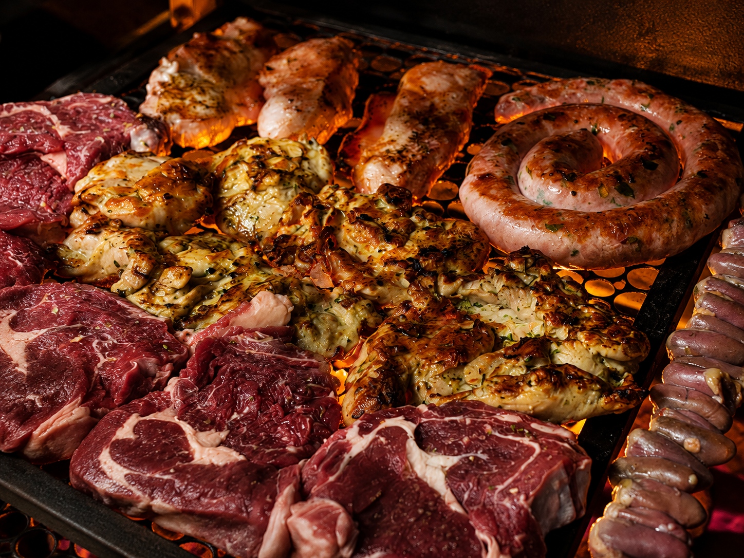 Foto de diversas carnes assando na churrasqueira